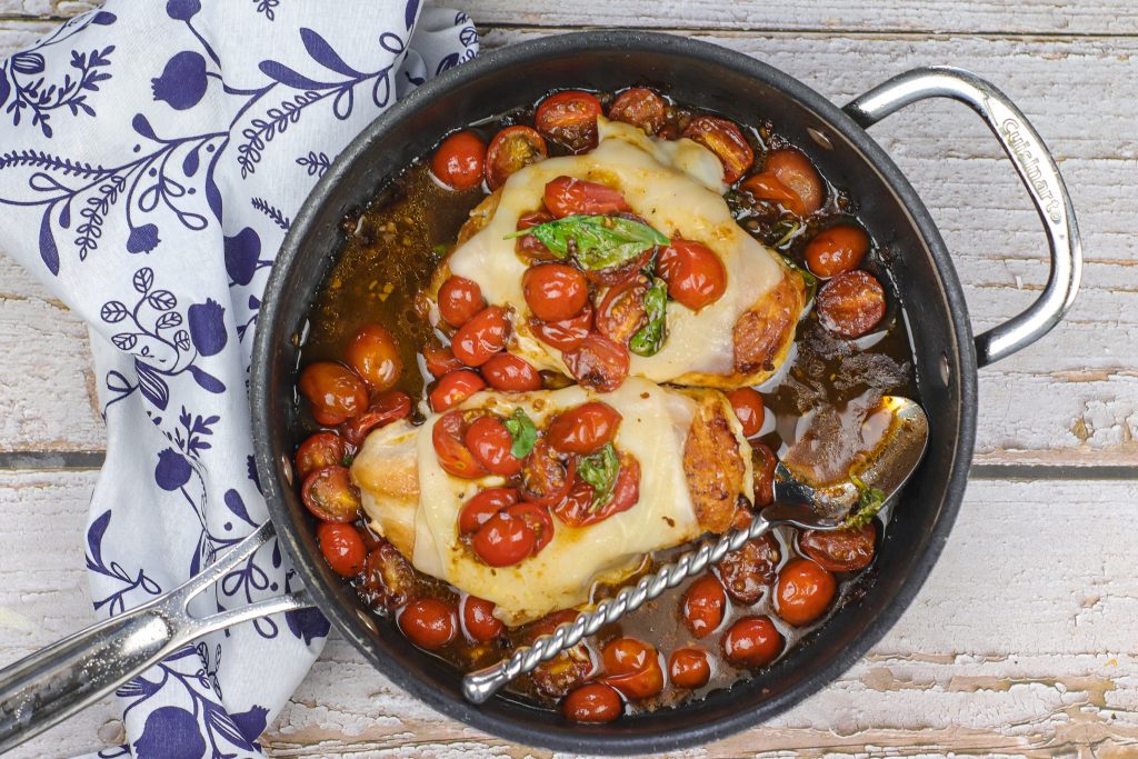 caprese chicken in a pan with a spoon