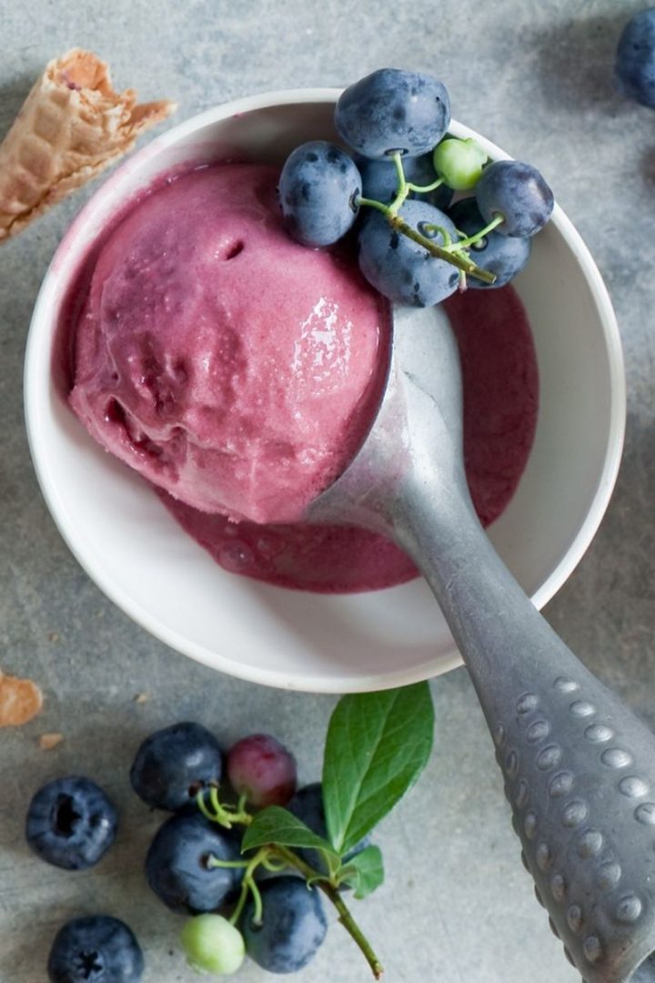 Berry Ice cream in a metal scoop in a  white bowl 