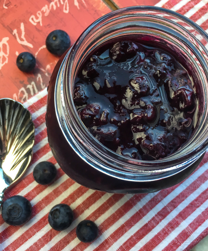 blueberry compote in a jar with a red background
