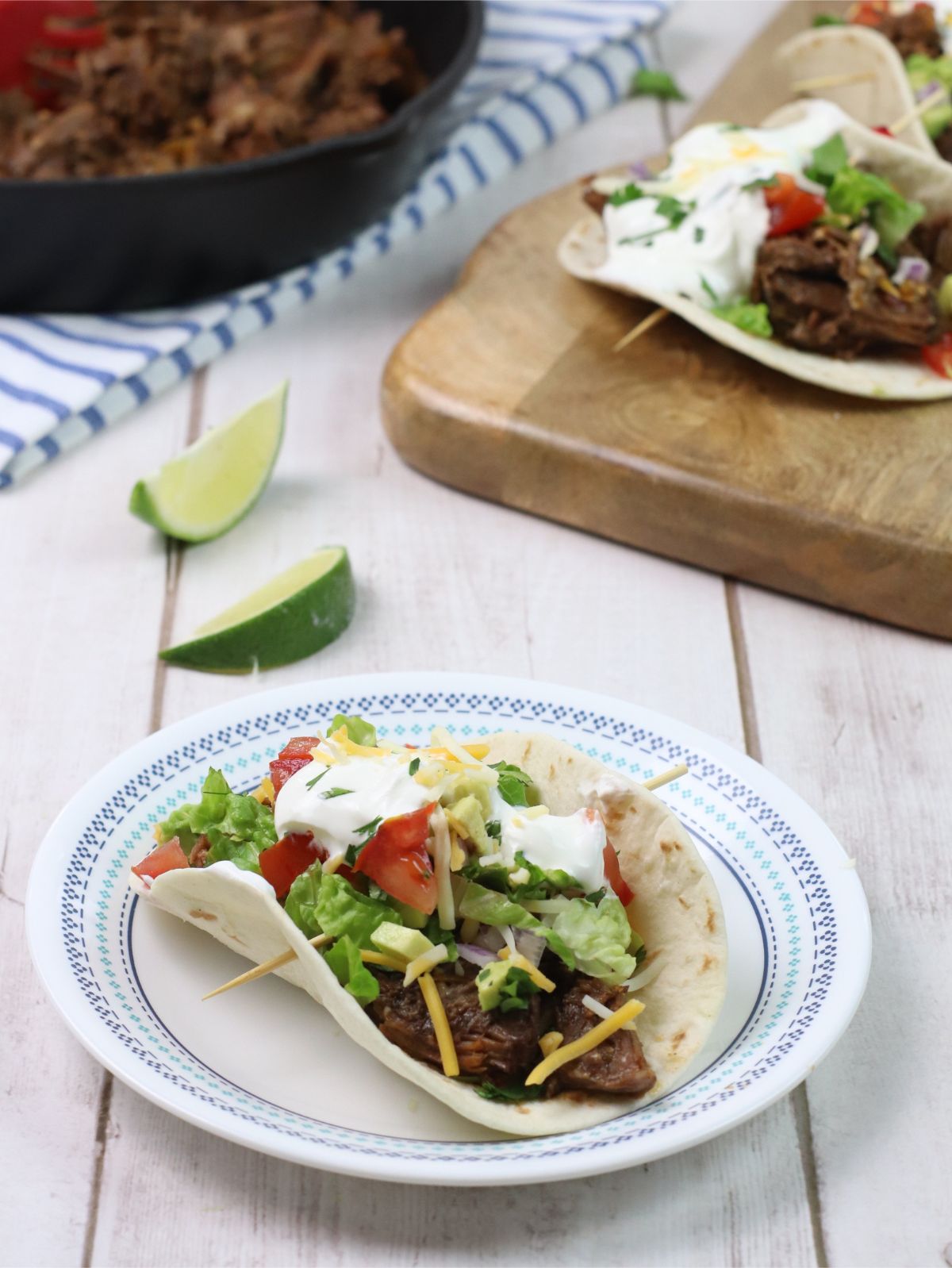 barbacoa taco on a white plate with a lime in the background