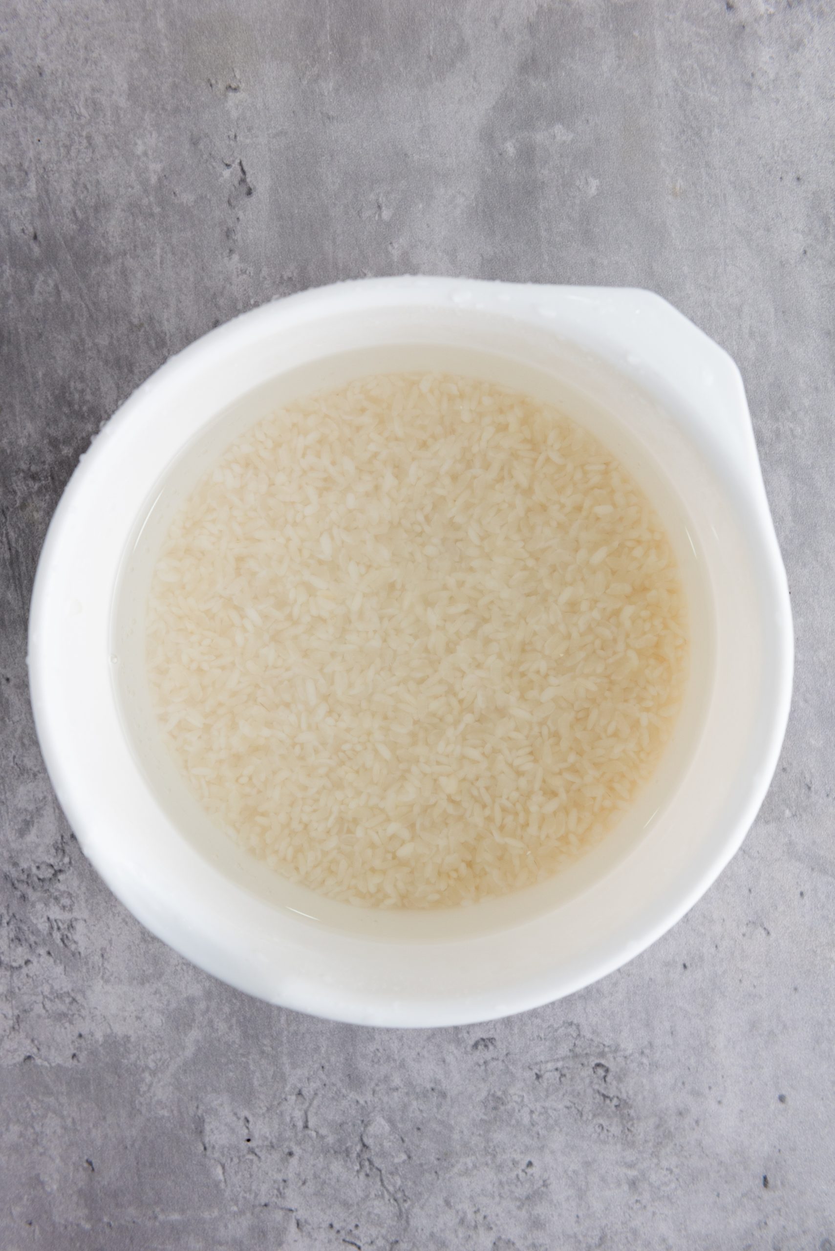 rice in a white bowl soaking in water