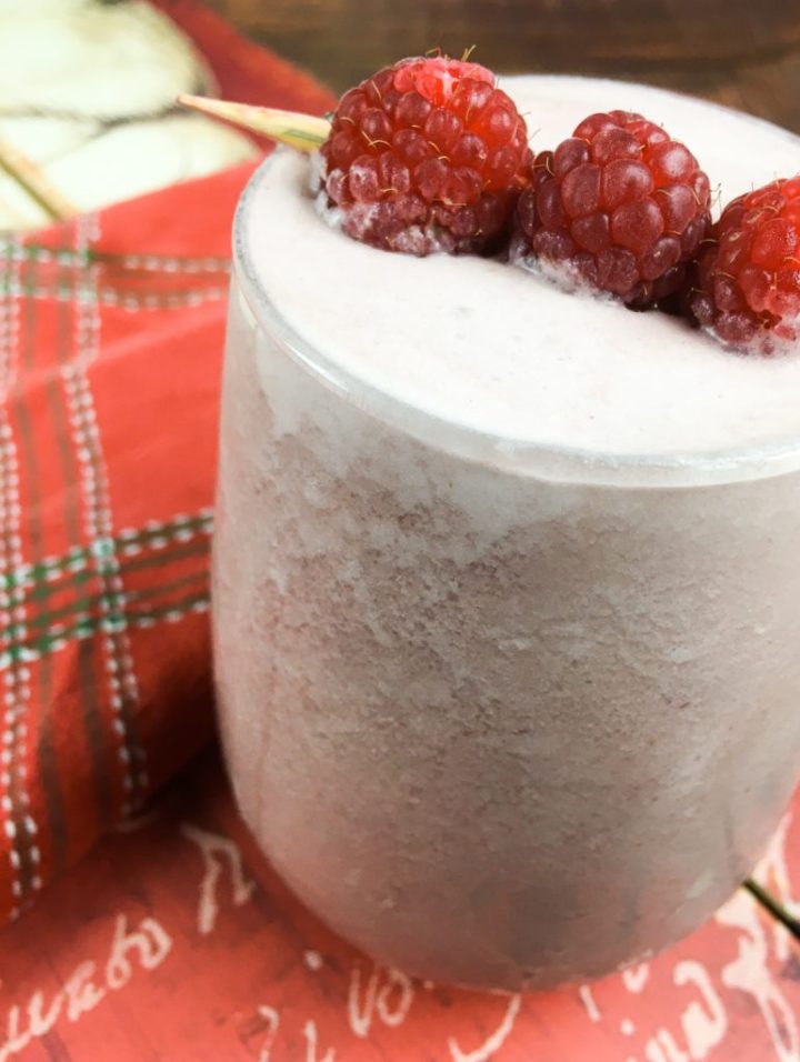 The recipe in a glass with a skewer of raspberries on top.