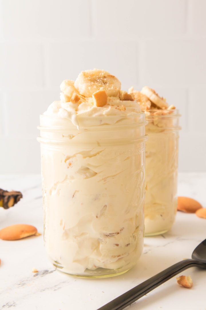 Banana pudding in a jar a with banana slices on top with another jar behind it