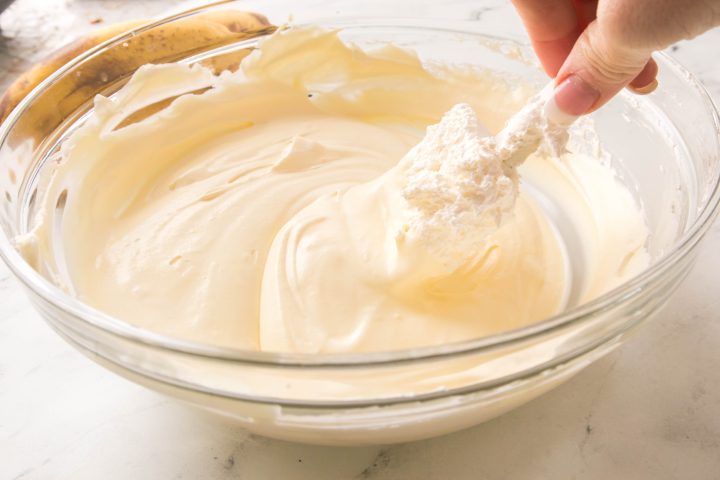 cool whip being folded into the pudding and milk mix