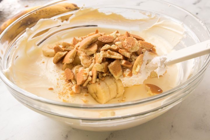 banana slices and crushed vanilla wafers being folded into the mix