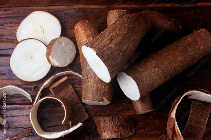 fresh cassava and peels and slices on rustic wooden table
